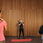 Fitness instructor leading a training session with two women in a modern gym setting.