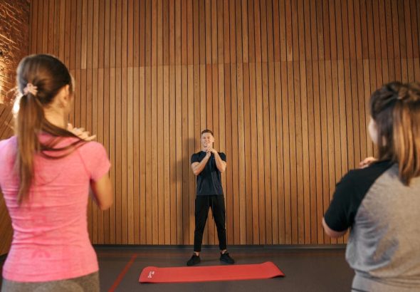 Fitness instructor leading a training session with two women in a modern gym setting.